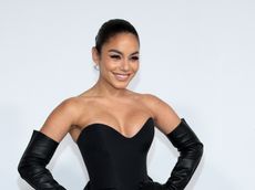 A headshot of Vanessa Hudgens smiling in a black strapless dress 