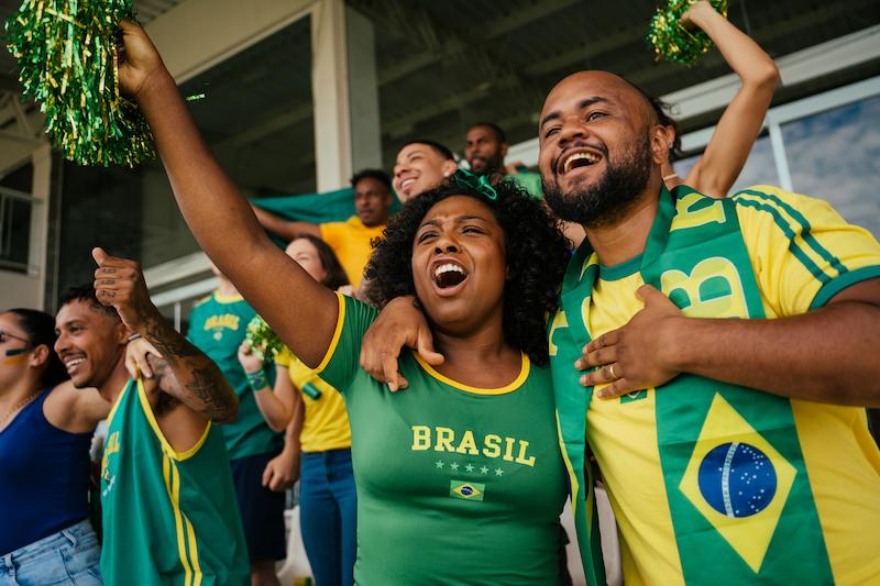 A group of people wearing Brazil football shirts cheering on the football players