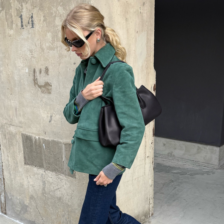 Model Elsa Hosk wears green suede jacket, dark wash jeans, and black almond-toe ballet flats.