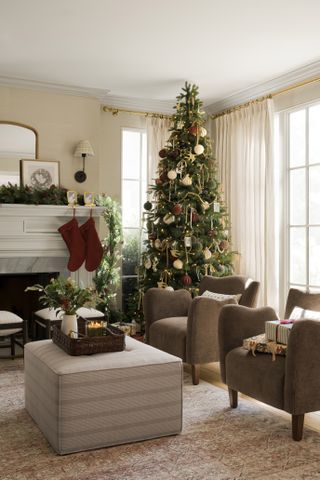 shea mcgee sitting next to a christmas tree with ornaments