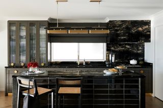 Black kitchen with granite countertop brought up wall and over extractor hood