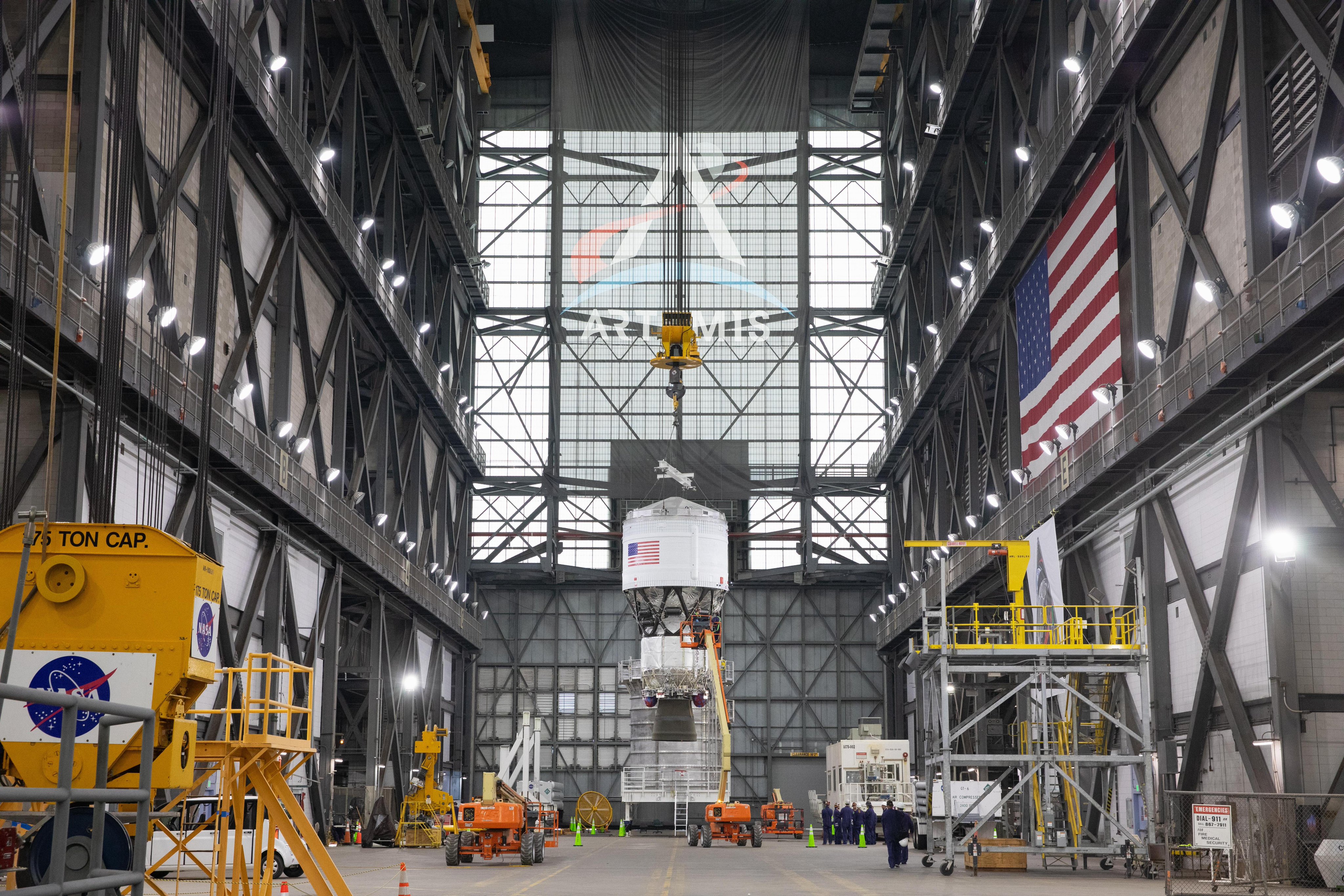 a large section of a rocket is hoisted in a factory