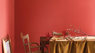 Dining room with red walls painted in 2023 paint color trend by Benjamin Moore