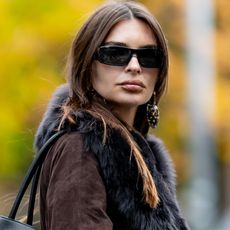 Emily Ratajkowski out in NYC wearing a Demellier New York bag and a brown suede belted jacket with a fur collar