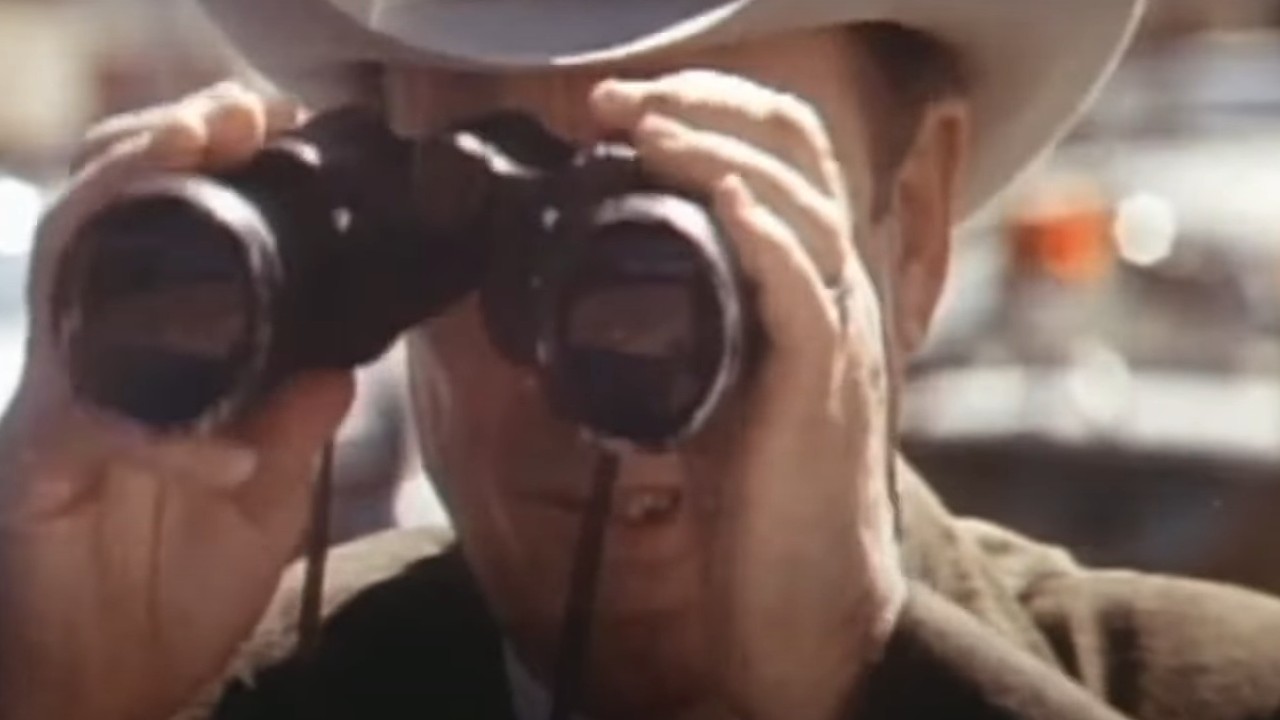 A cop peering through binoculars in The Sugarland Express
