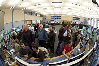 Scientists watch particle collision data inside the LHC control room.