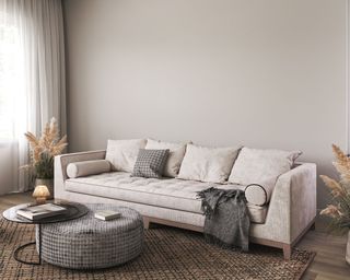 neutral living room with beige walls and sofa and gray ottoman