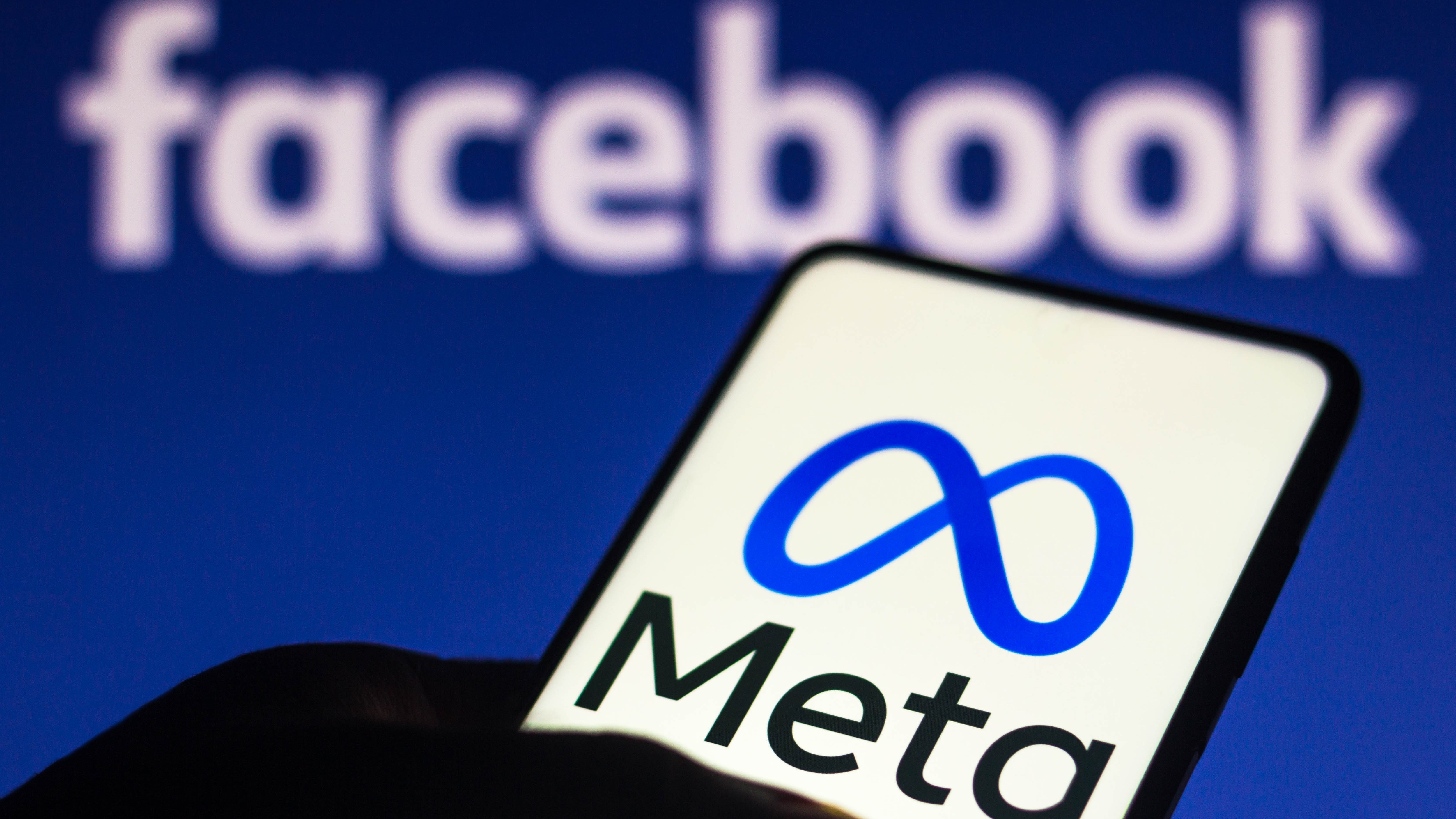 Logo Meta pada smartphone di depan logo Facebook sedikit kabur di latar belakang