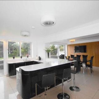 Open plan kitchen with black units and white worktop