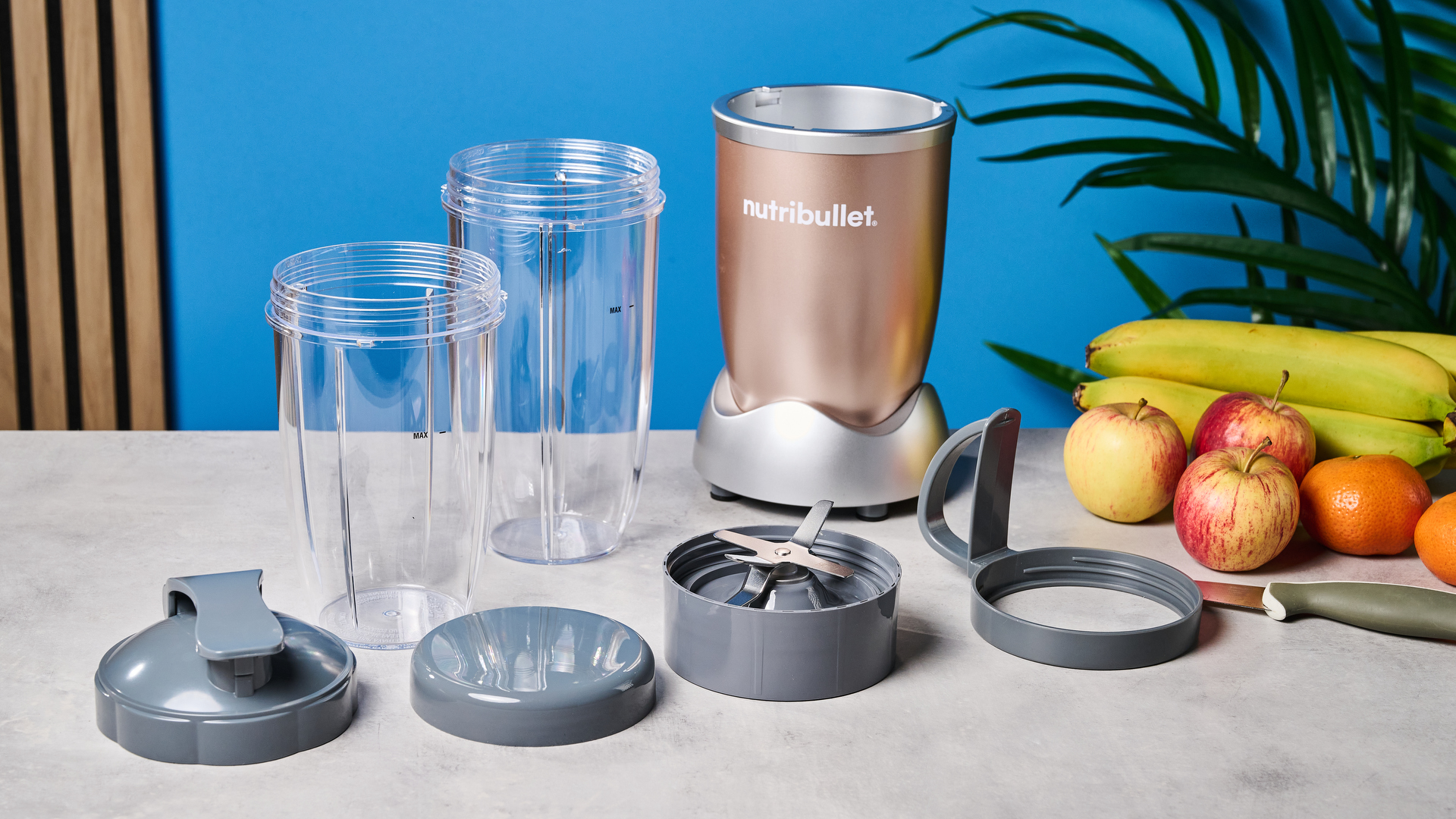 a champagne nutribullet pro 900w with fruit in the shot and a blue background