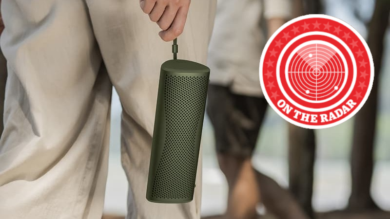 Someone holding a green KEF Muo speaker by the carrying handle
