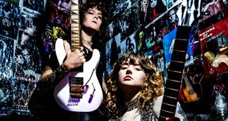 Tailgunner's Rhea Thompson and Zach Salvini pose in heavily postered backstage area with Jackson and Framus guitars