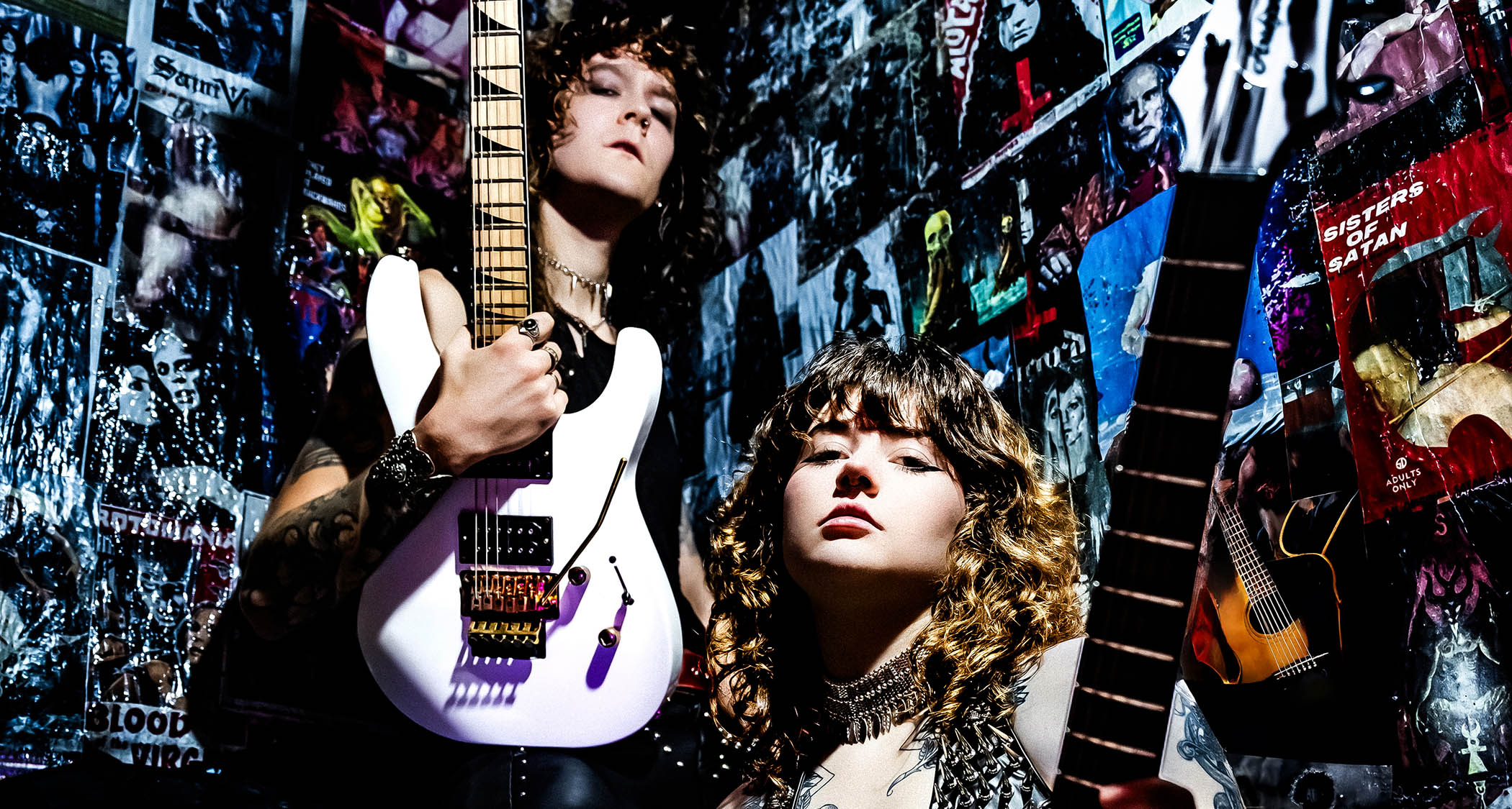 Tailgunner's Rhea Thompson and Zach Salvini pose in heavily postered backstage area with Jackson and Framus guitars