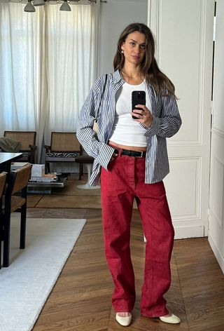 a photo showing what colors go with red, specifically a woman wearing a red jeans and white tank and blue button-down shirt