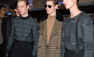A side shot of three models posing for a different camera in grey and brown knitwear