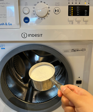 A cup of baking soda in front of a washing machine