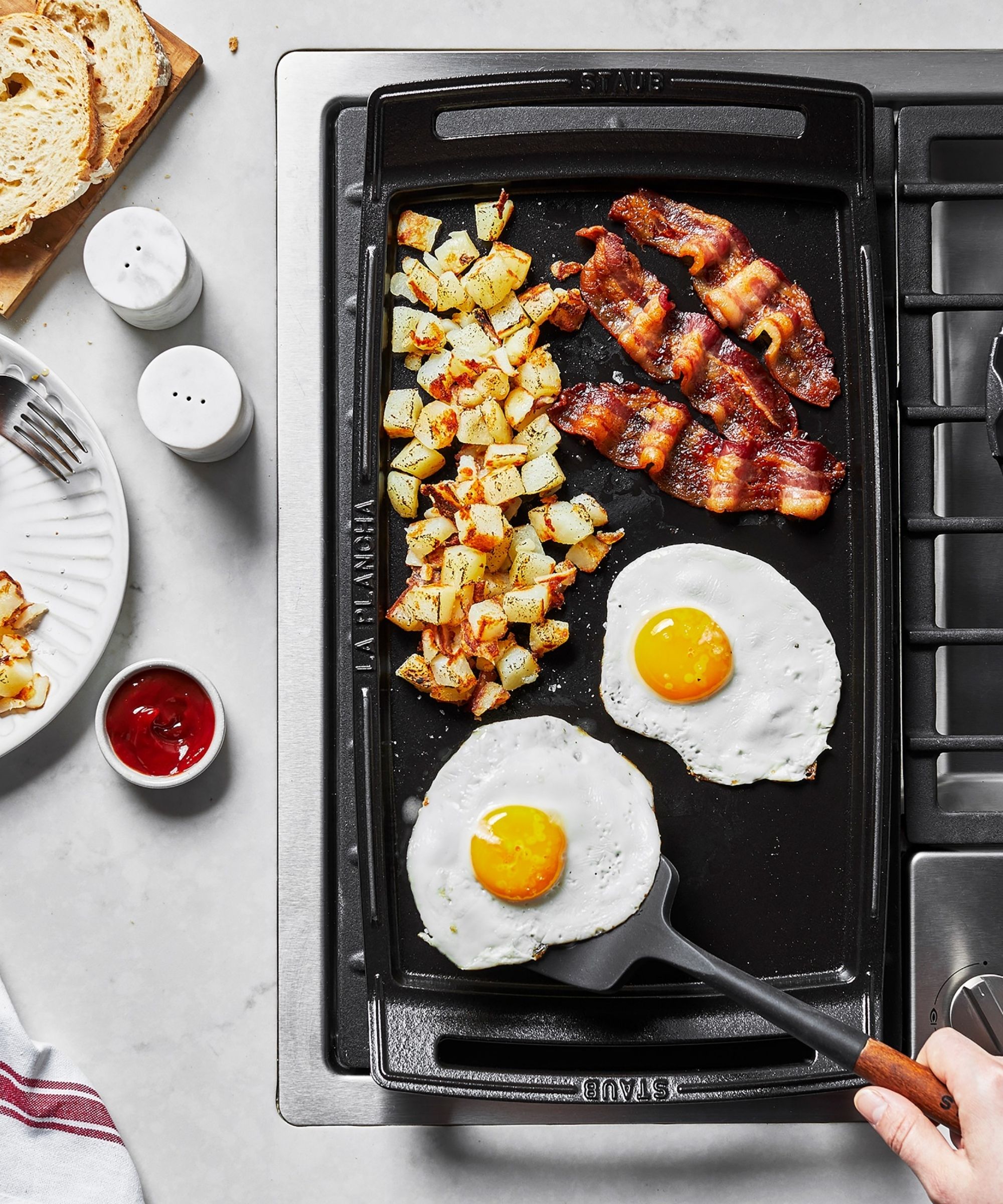 Griddle with fried eggs, bacon rashers and potatoes