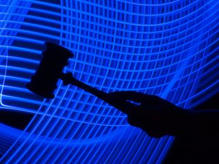 Big tech: A photo of a silhouette of a hand holding a gavel is in the foreground, with a futuristic mesh of blue lines in the background to imply regulation of tech companies