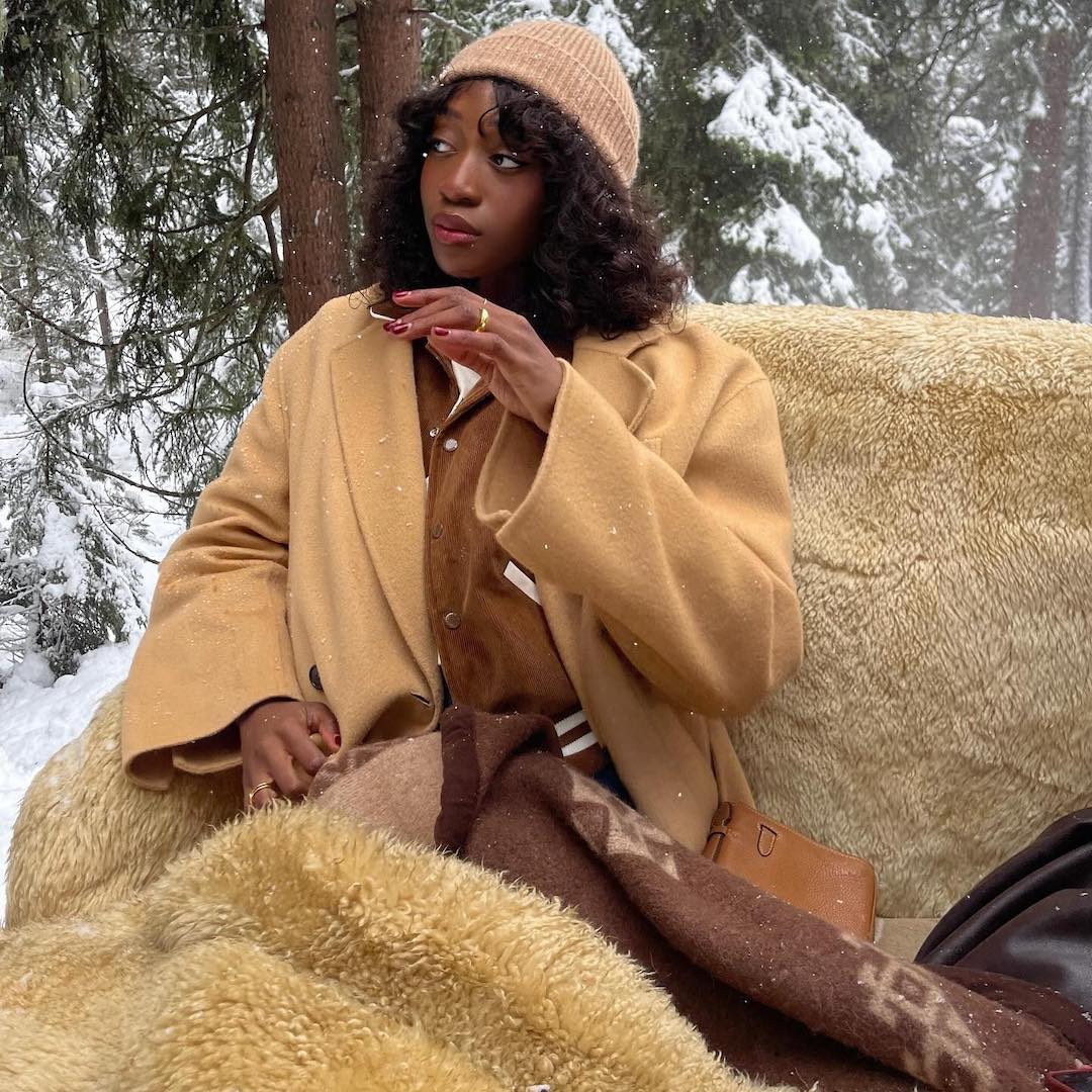 Emmanuelle Koffi wearing beanie hat and beige trench in cosy blankets - best comfort blanket perfumes
