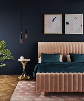 pink bed in a dark navy bedroom with framed artwork