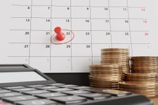 Calendar with a red pushpin on the 22nd circled in red next to stacks of coins and a calculator