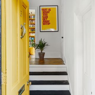 Entrance with yellow front door and black and white steps to living area