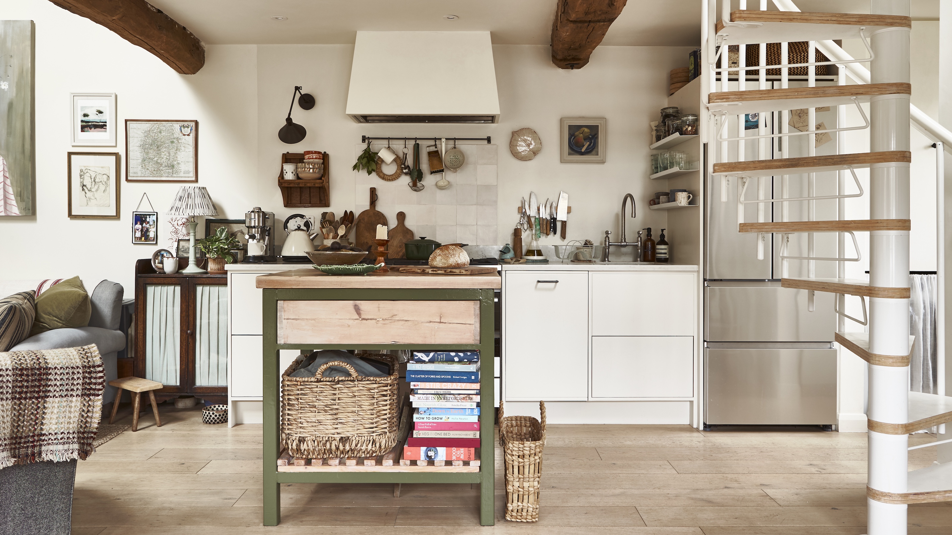 galley kitchen with small island with green metal frame and spiral staircase 