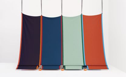 A tent made of four fabric rectangles in purple, blue, aqua green and orange photographed against a white background