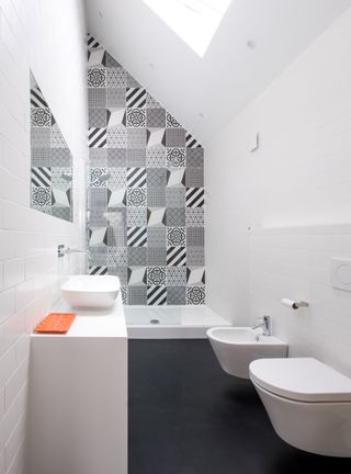 An en-suite bathroom in a loft converand a rear tiled feature wall in black and whitesion with sloped wall