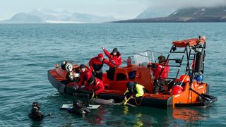 Several people clamber around a boat in the ocean while taking various measurements