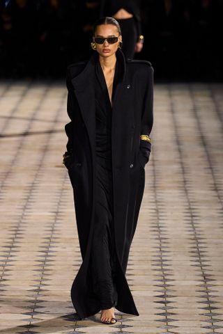 Saint Laurent model walks the spring/summer 2023 runway wearing a maxi coat