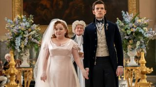 (L to R) Nicola Coughlan as Penelope Featherington, James Duke as Minister Hughes, Luke Newton as Colin Bridgerton holding hands right after getting married.