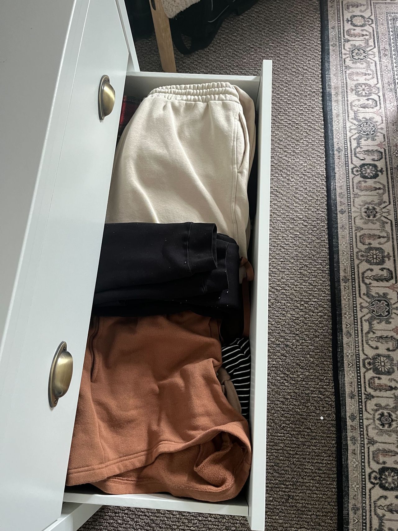 A messy, unorganized dresser drawer with shorts and leggings