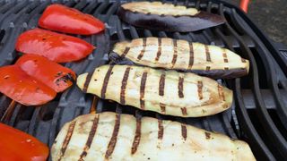 Eggplant slices cooking on a grill with wavy griddle lines