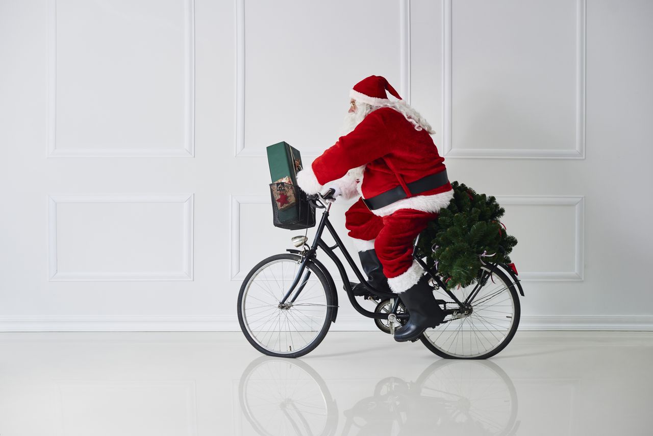 Santa Claus riding a bicycle with a present in the basket