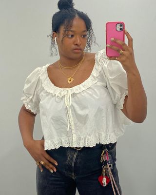 Imani Randolph wearing gold necklaces, a white embroidered top, and dark jeans.