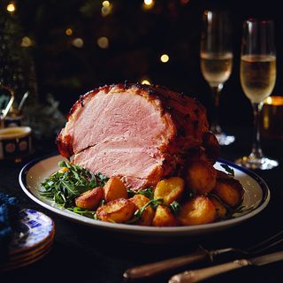 Roast potatoes served with ham and vegetables on serving dish