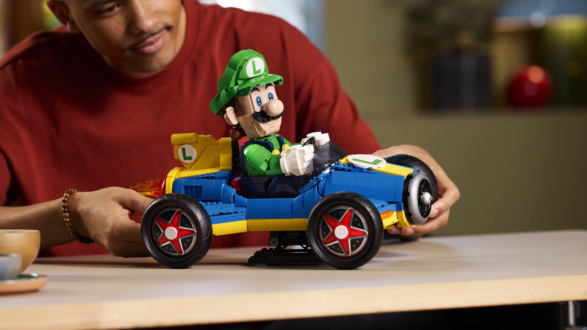 Lego Luigi & Mach 8 set being adjusted by a man sat at a wooden table