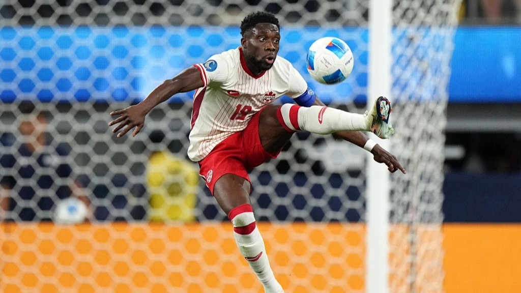 Canada captain Alphonso Davies jumps into mid-air to control a ball with his left foot.