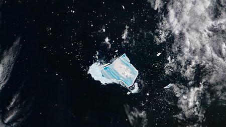 Satellite photo of an iceberg covered with vibrant blue stripes in the middle of the ocean