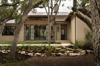 A neutral-painted home surrounded by oak trees