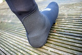 The Spatz Fasta overshoe beoing worn by a rider standing on a wooden deck