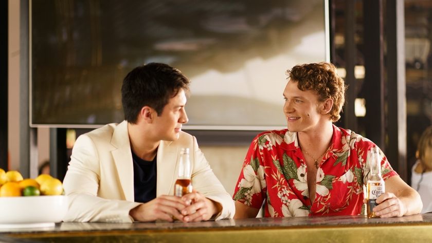 Shane (Hudson Williams), dressed in a smart beige suit and nursing a beer, sits beside Ilya (Connor Storrie), who sports a red and white floral shirt, as they shoot the breeze in a Tampa Bay bay in Miami.