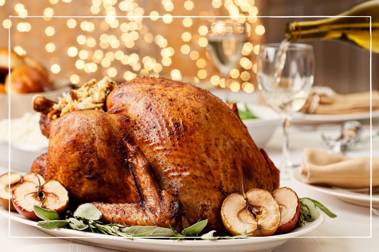 Cooked turkey on dining table surrounded by glassware and christmas lights