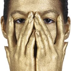 Woman's face and hands covered in gold body paint