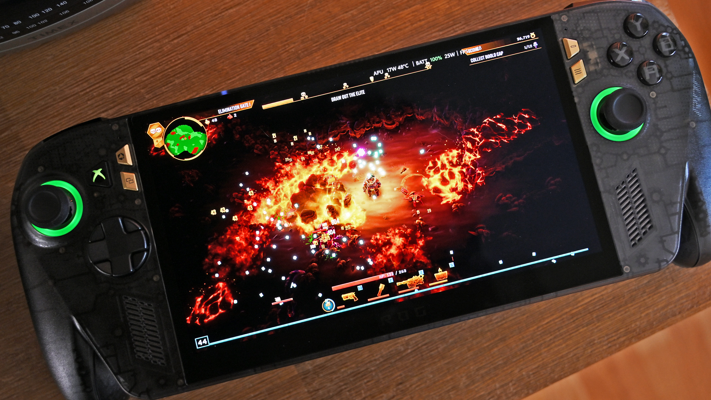 Top-down view of the ROG Ally X20 handheld running an action game with fiery explosions, showing green glowing joystick rings and a dbrand custom skin.