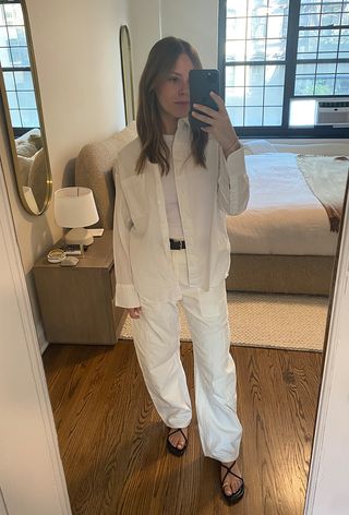 Editor taking a selfie in an all-white outfit with carpenter pants.