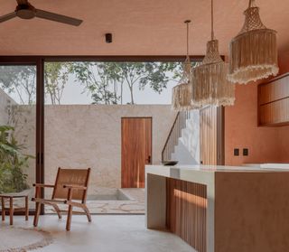 A kitchen with pink limewash walls and concrete island