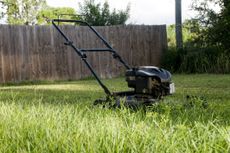 A freshly cut green lawn with a lawn mower in the middle