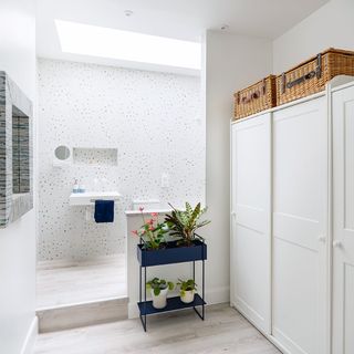 white ensuite bathroom with wardrobes and plant stand